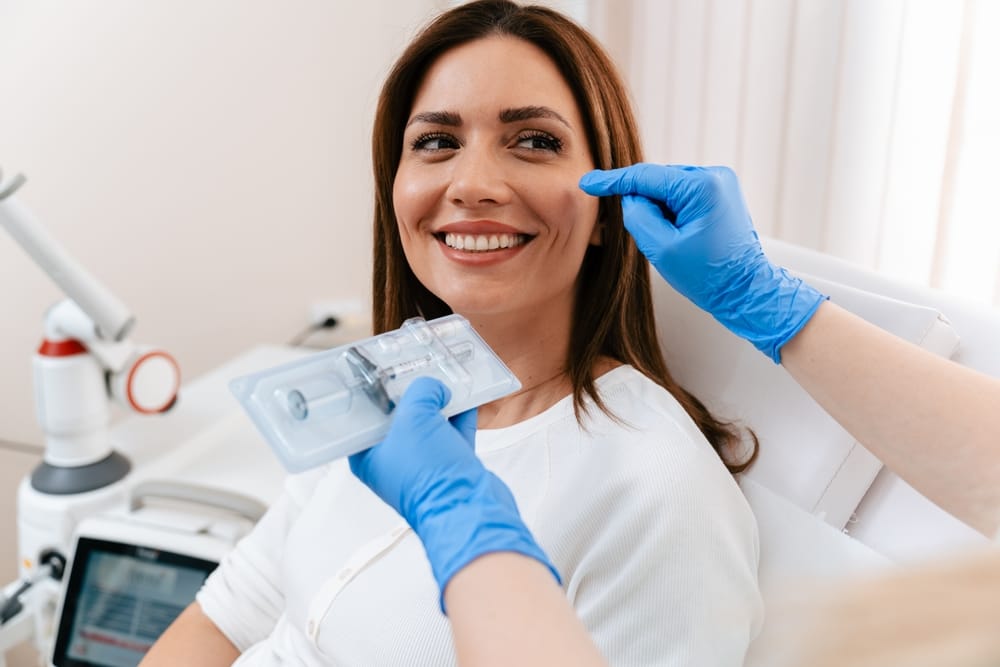 Patient Smiling During Facial Injectable Treatment Consultation – Dermal Fillers Woman Receiving Facial Assessment for Cosmetic Injectable Enhancement in a Medical Setting – Dermal Fillers